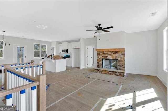 living room featuring ceiling fan with notable chandelier and a fireplace