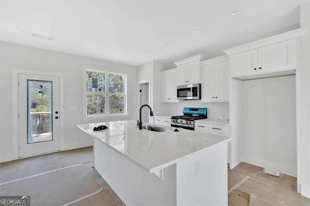 kitchen with sink, stainless steel appliances, an island with sink, and white cabinets