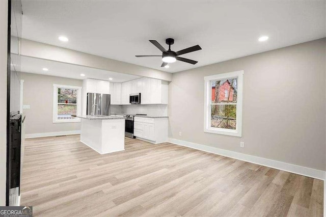 kitchen featuring light hardwood / wood-style flooring, white cabinetry, stainless steel appliances, tasteful backsplash, and a center island with sink