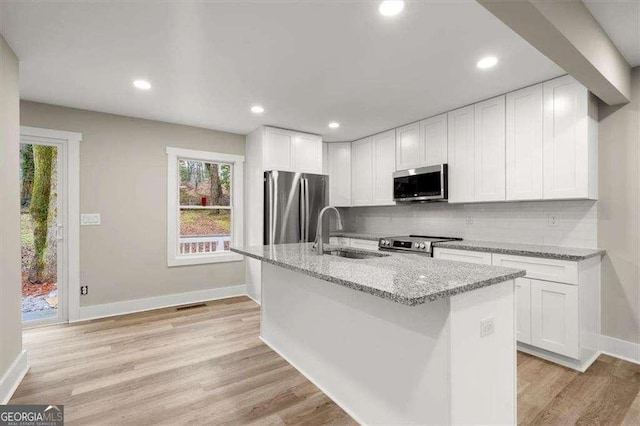 kitchen featuring white cabinetry, appliances with stainless steel finishes, sink, and light stone counters