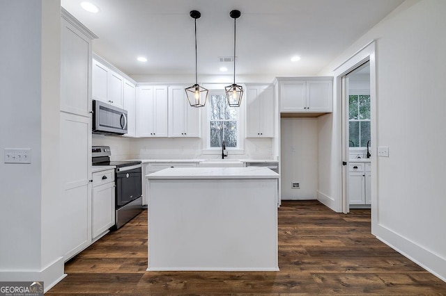 kitchen featuring white cabinetry, hanging light fixtures, a center island, stainless steel appliances, and dark wood-type flooring