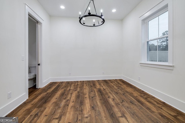 empty room featuring dark wood-type flooring and a chandelier