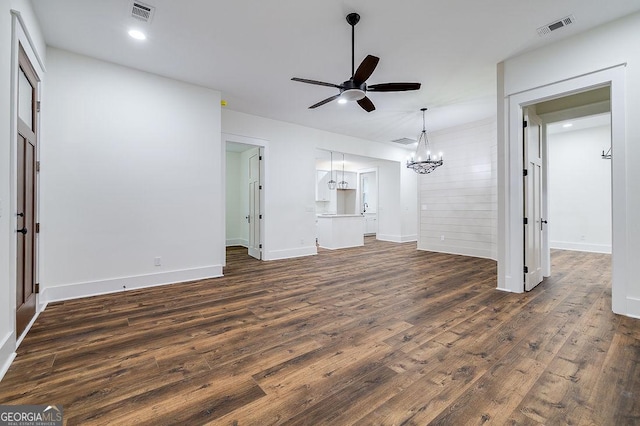 unfurnished living room featuring dark hardwood / wood-style floors and ceiling fan with notable chandelier