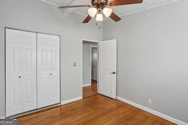 unfurnished bedroom with wood ceiling, ceiling fan, hardwood / wood-style floors, a closet, and beamed ceiling