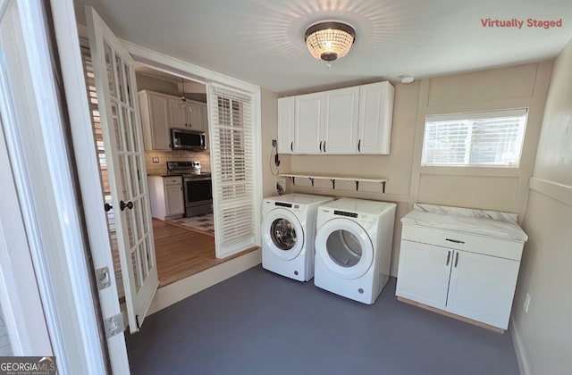 clothes washing area with cabinets and washer and clothes dryer