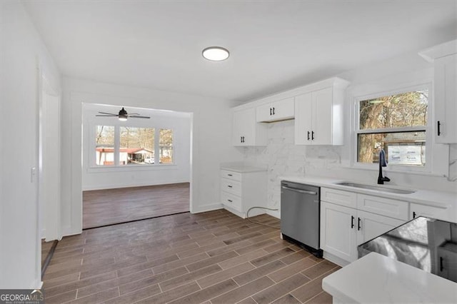 kitchen with a wealth of natural light, tasteful backsplash, sink, white cabinets, and stainless steel dishwasher