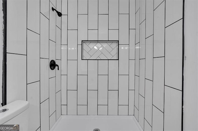 bathroom featuring a tile shower and toilet