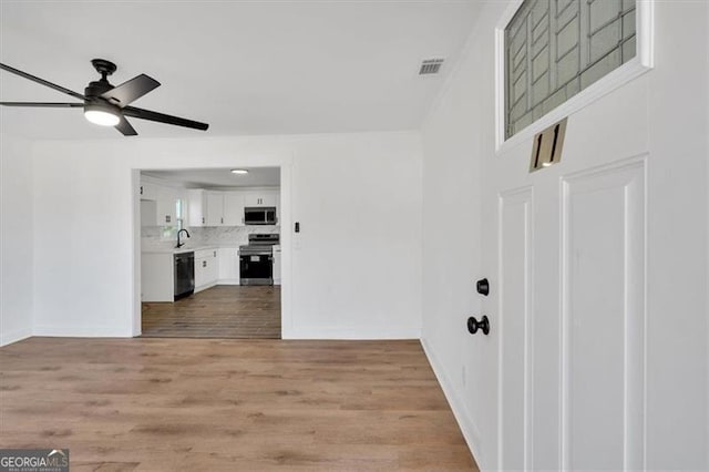 interior space with sink, ceiling fan, and light hardwood / wood-style flooring