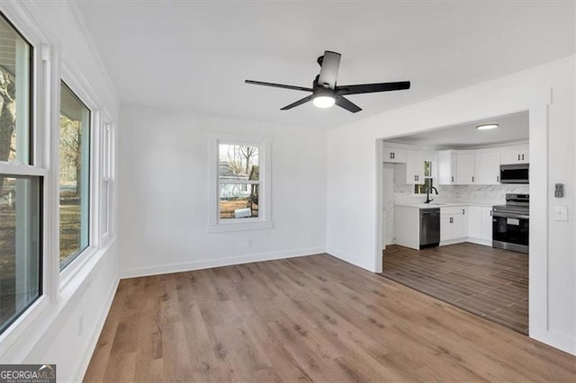 unfurnished living room featuring ceiling fan, a healthy amount of sunlight, sink, and light hardwood / wood-style flooring