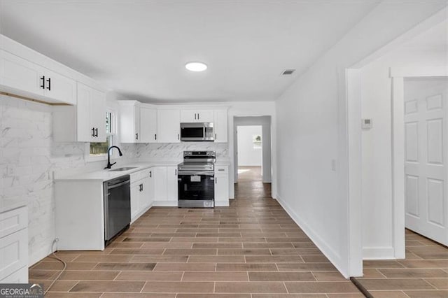 kitchen featuring stainless steel appliances, a wealth of natural light, sink, and white cabinets