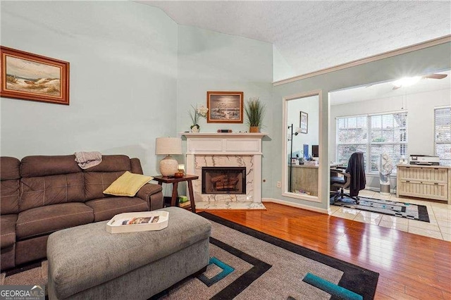 living room featuring lofted ceiling, hardwood / wood-style flooring, a fireplace, and a textured ceiling