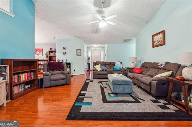 living room featuring ceiling fan, a textured ceiling, and light wood-type flooring