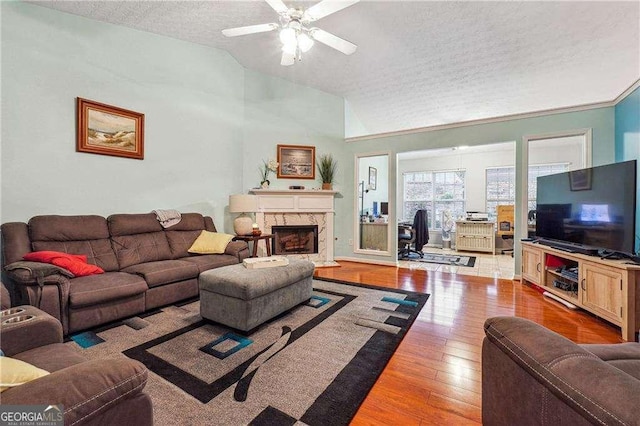 living room featuring vaulted ceiling, ceiling fan, hardwood / wood-style floors, and a textured ceiling