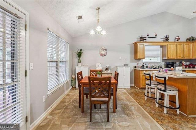 dining room featuring an inviting chandelier, vaulted ceiling, and a textured ceiling