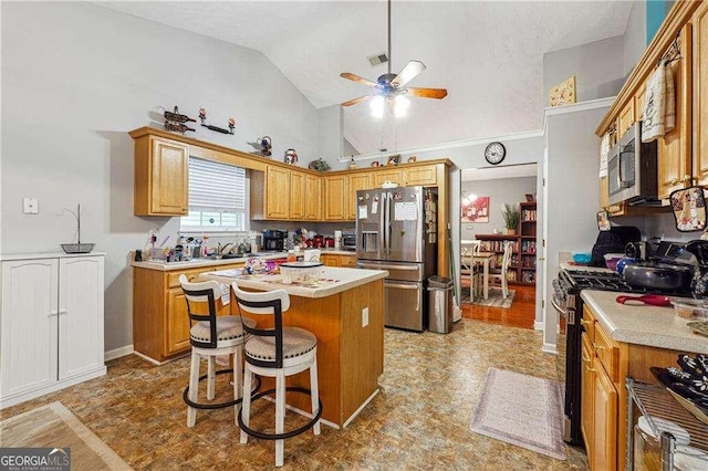 kitchen with a kitchen island, appliances with stainless steel finishes, high vaulted ceiling, a kitchen breakfast bar, and ceiling fan