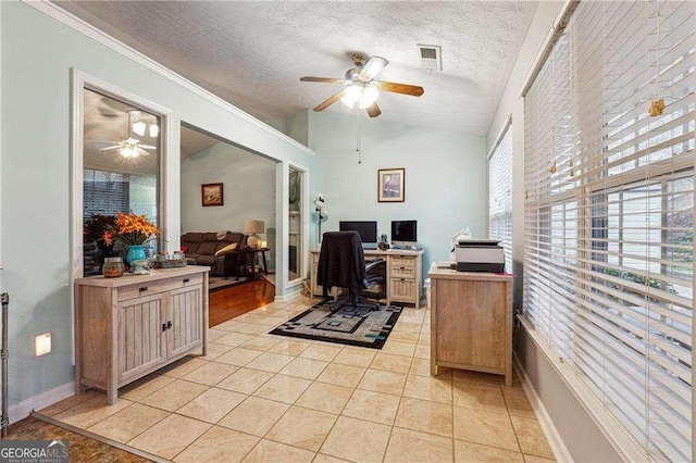 home office featuring ceiling fan, lofted ceiling, light tile patterned floors, and a textured ceiling