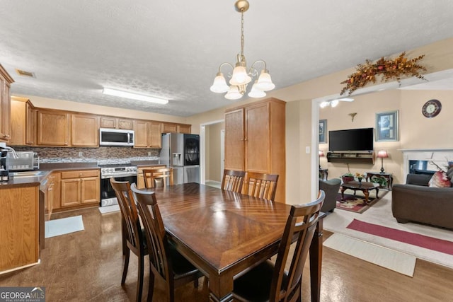 dining area featuring dark wood-type flooring, an inviting chandelier, and a textured ceiling