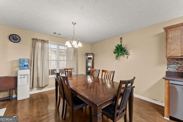 dining room with dark wood-type flooring, a notable chandelier, and a textured ceiling