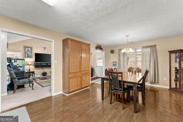 dining room with dark wood-type flooring, a textured ceiling, and a notable chandelier