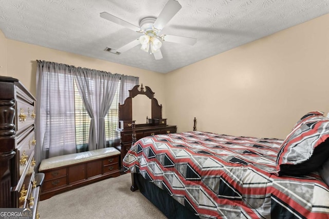 bedroom with ceiling fan, light colored carpet, and a textured ceiling