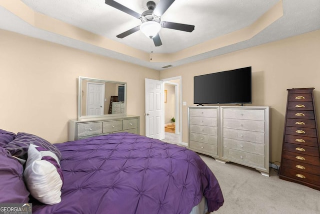 carpeted bedroom featuring ceiling fan and a raised ceiling