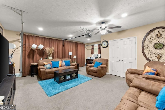 carpeted living room featuring ceiling fan and a textured ceiling