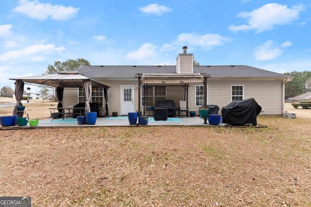 rear view of property featuring a gazebo, a pergola, a patio area, and a lawn