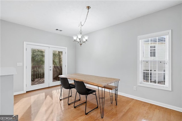 dining area with light hardwood / wood-style flooring, an inviting chandelier, and french doors