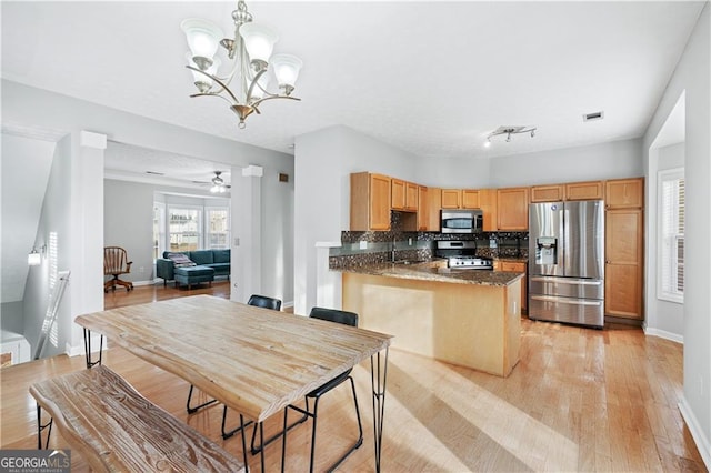 kitchen featuring appliances with stainless steel finishes, pendant lighting, tasteful backsplash, light hardwood / wood-style floors, and kitchen peninsula