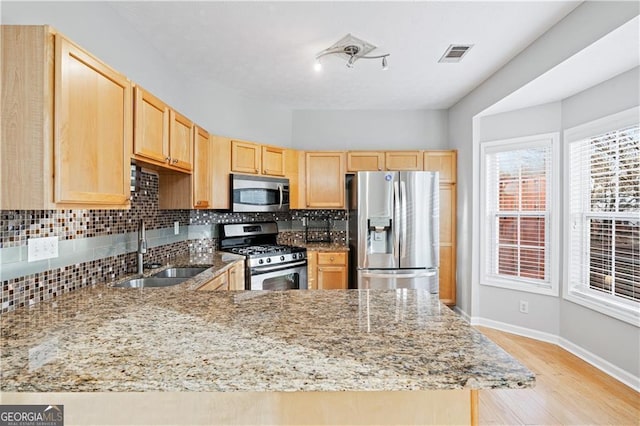 kitchen with sink, stainless steel appliances, light stone countertops, decorative backsplash, and light brown cabinets