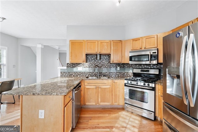 kitchen featuring sink, stainless steel appliances, light stone counters, decorative backsplash, and light brown cabinets