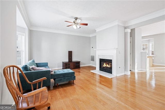 living room featuring hardwood / wood-style floors, crown molding, a premium fireplace, and ceiling fan