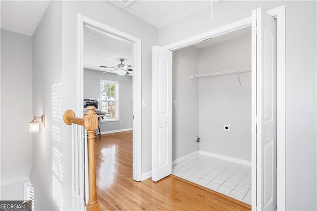 laundry area with ceiling fan, wood-type flooring, hookup for an electric dryer, and a textured ceiling