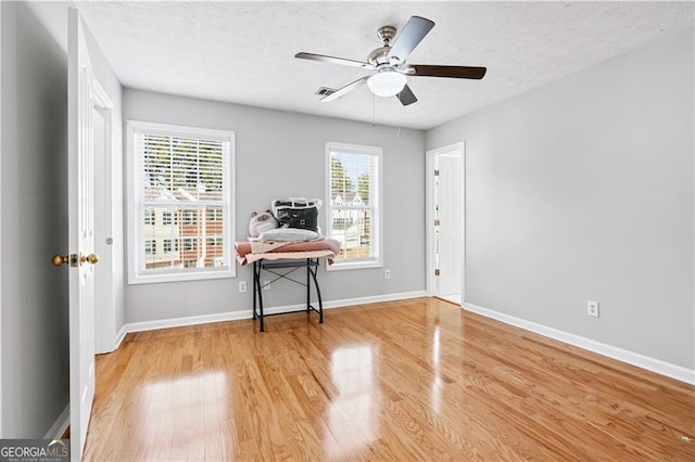 interior space featuring ceiling fan, hardwood / wood-style flooring, and a textured ceiling