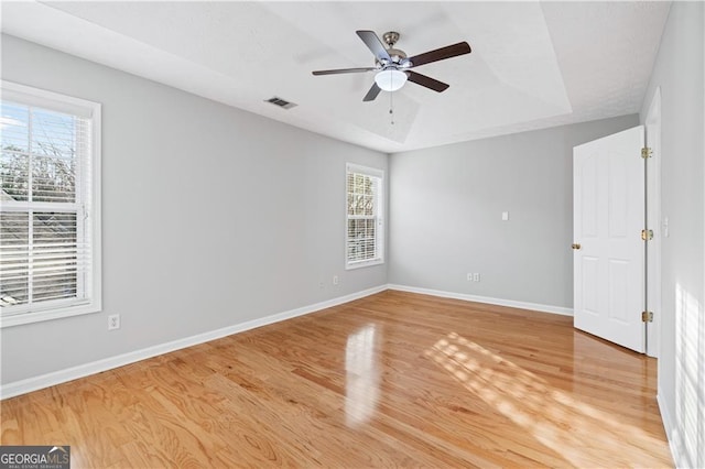 unfurnished room featuring wood-type flooring, ceiling fan, and a tray ceiling