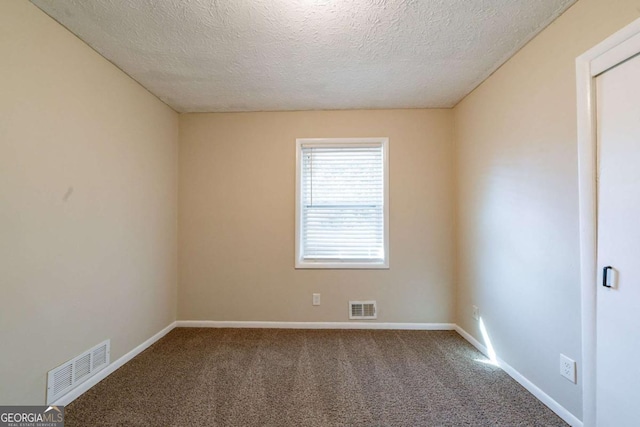 empty room with carpet flooring and a textured ceiling