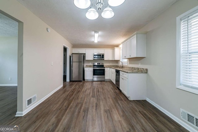 kitchen featuring sink, white cabinetry, stainless steel appliances, dark hardwood / wood-style floors, and light stone counters