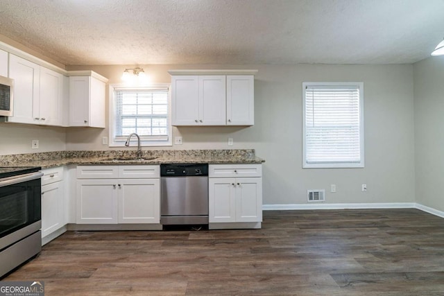 kitchen with white cabinetry, sink, dark hardwood / wood-style flooring, stainless steel appliances, and light stone countertops