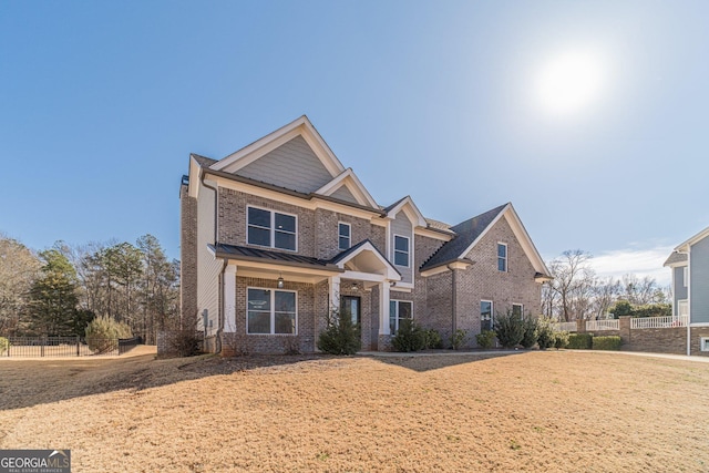 craftsman house with brick siding, metal roof, a standing seam roof, fence, and a front yard