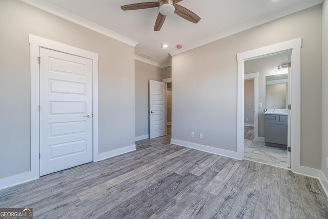 unfurnished bedroom with ceiling fan, light hardwood / wood-style floors, ornamental molding, a spacious closet, and a closet