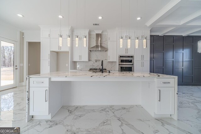 kitchen with a spacious island, pendant lighting, light stone countertops, and wall chimney range hood