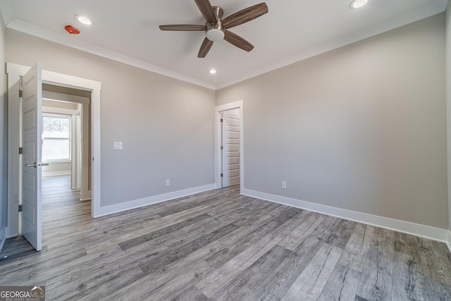 empty room featuring ornamental molding, recessed lighting, wood finished floors, and baseboards