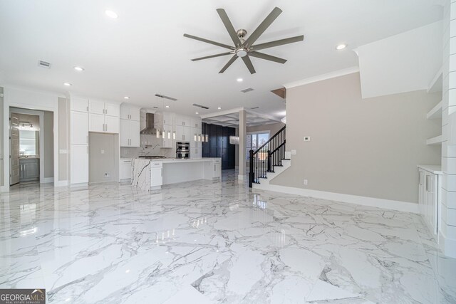 unfurnished living room featuring ornamental molding and ceiling fan