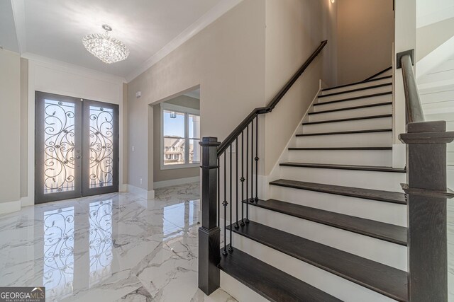 foyer featuring french doors, ornamental molding, and an inviting chandelier