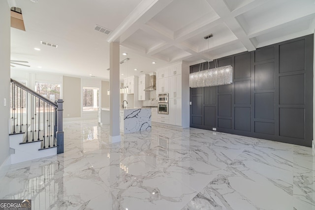 interior space featuring coffered ceiling, stairway, visible vents, and a decorative wall