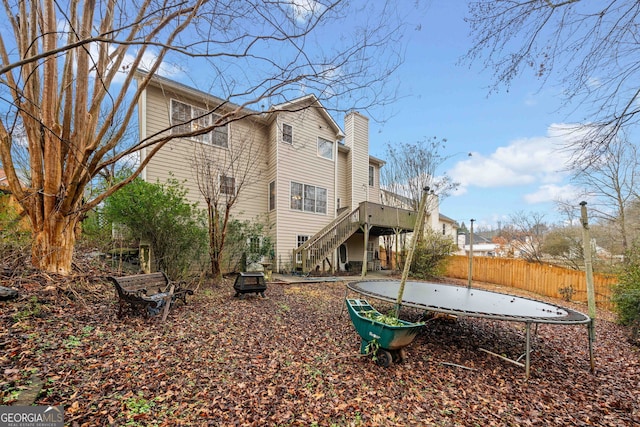 rear view of property with a trampoline and a deck