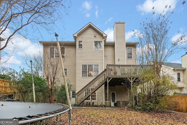 back of house with a trampoline and a wooden deck