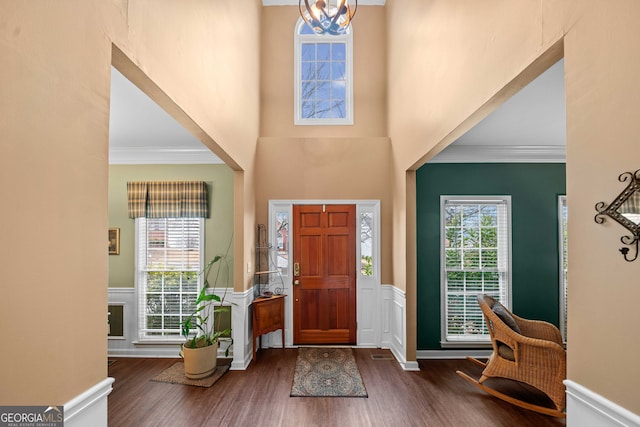 foyer with dark hardwood / wood-style flooring, a notable chandelier, and crown molding