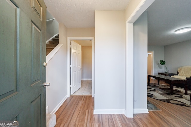 hallway with light hardwood / wood-style flooring and a textured ceiling