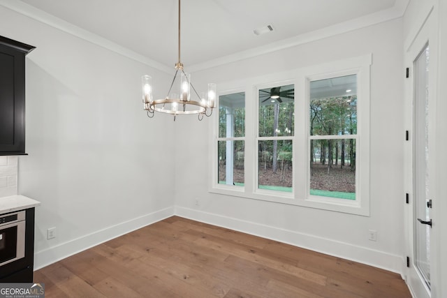 unfurnished dining area with crown molding, hardwood / wood-style floors, and an inviting chandelier